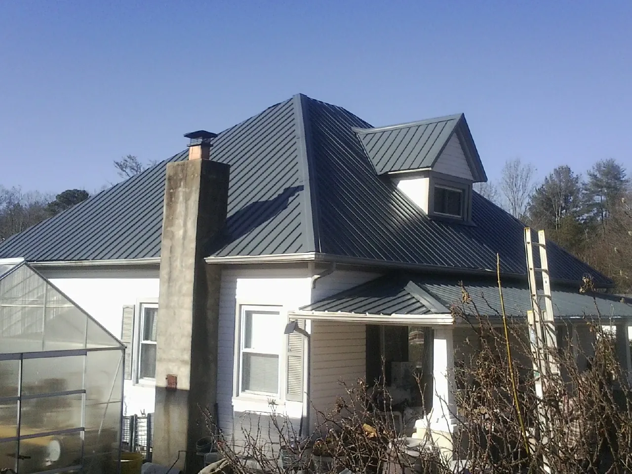 Dark blue standing seam metal roof on a white farmhouse with dormer — Slate & Tile Roof Repair by Roofing Brothers in Columbia Station
