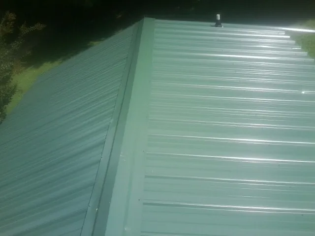 New green metal panels meeting at the ridge of a roof — Flat Roof Repair work by our crew in Columbia Station