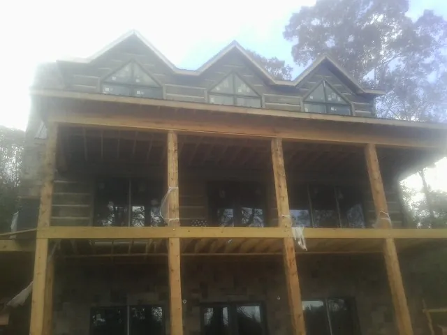 Dormers and porch framing on a large log home under construction — Roof Coating work by our crew in Columbia Station