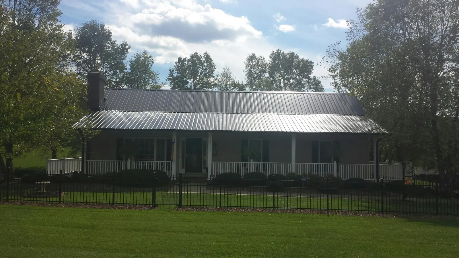 Gray metal roof on a brick ranch with a full width front porch — Gutter Guard Installation work by our crew in Columbia Station