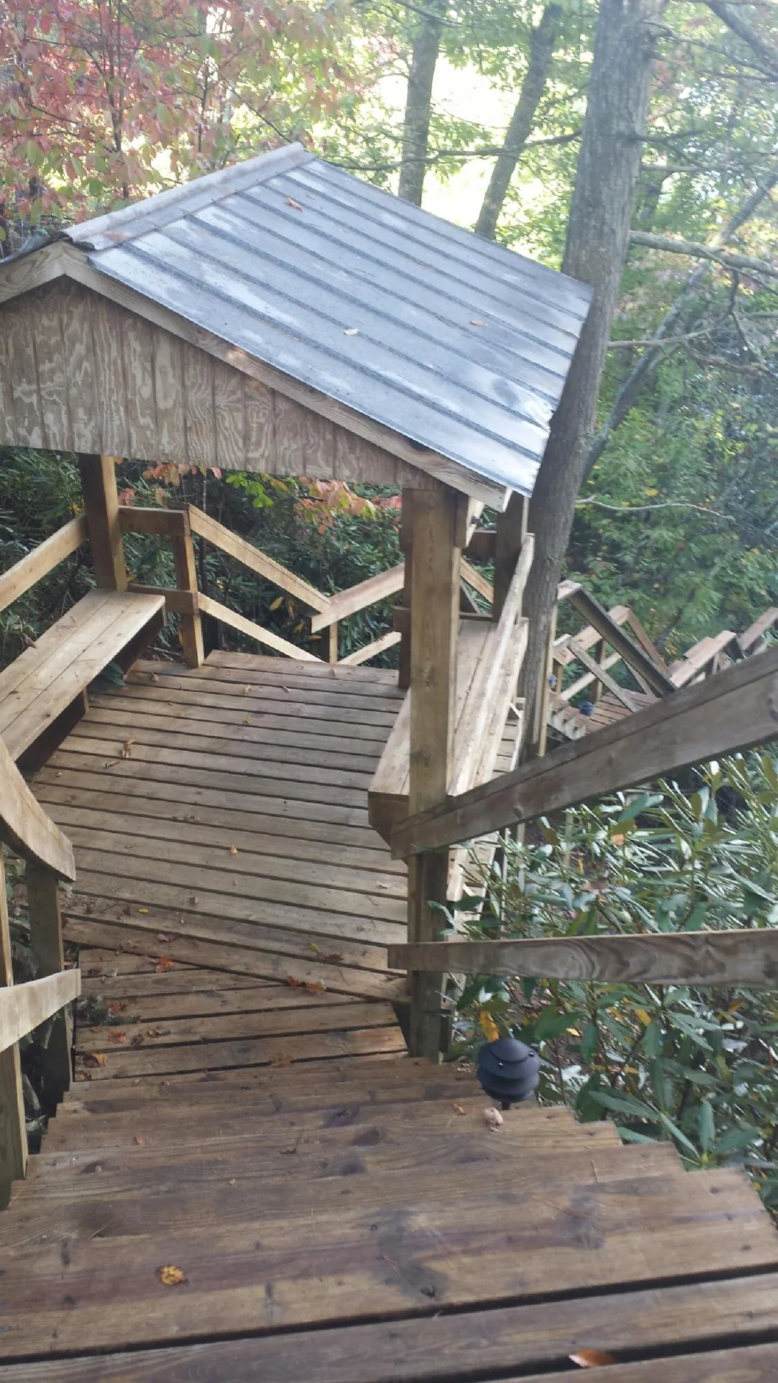 Metal roofed shelter over wooden steps on a wooded walkway — Skylight Repair & Installation work by our crew in Columbia Station