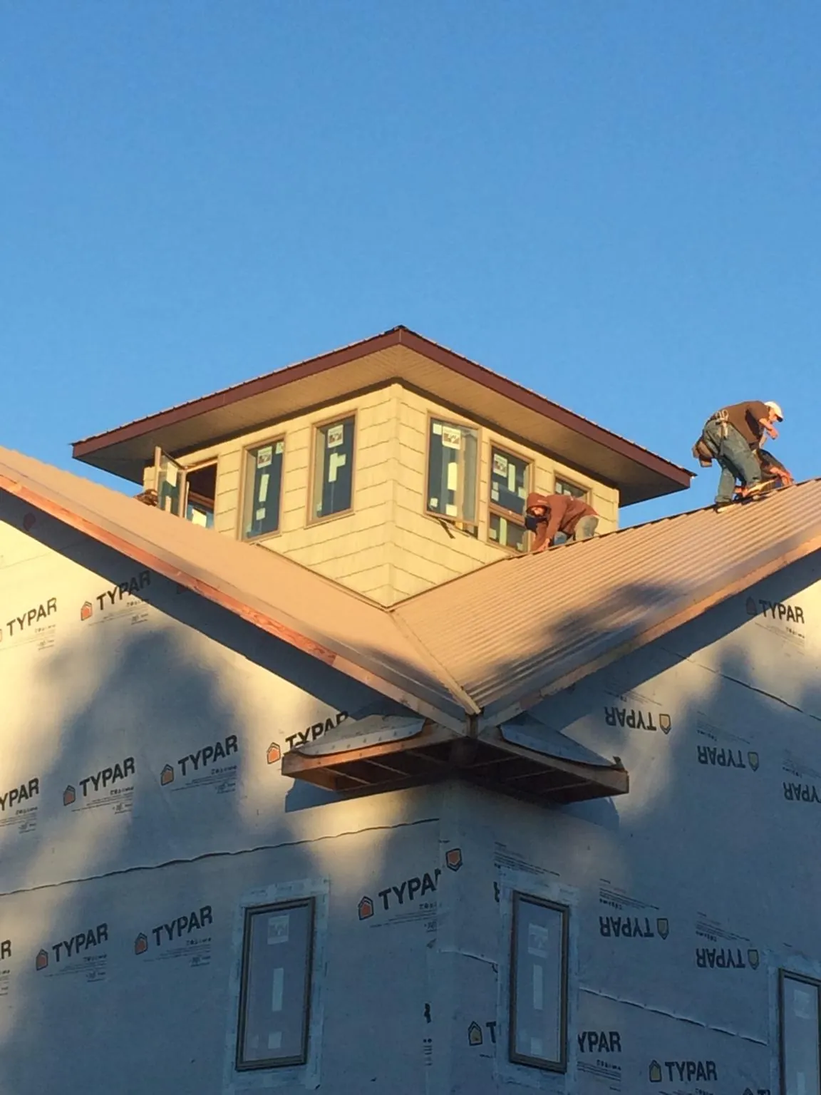 Roofers working around a rooftop cupola on a new metal roof at sunset — Roof Waterproofing in Columbia Station by Roofing Brothers